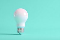White light bulb on mint green background, minimalist composition for creative concept, innovation, or energy efficiency themes.