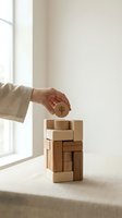 Hand placing wooden coin with tree symbol on top of stacked wooden blocks representing sustainable investment and eco-friendly business growth concept.