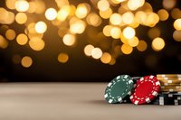 Stacked poker chips against blurred golden bokeh lights background, creating atmospheric casino gambling ambiance with red and green gaming tokens.