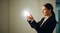 Professional businesswoman holding glowing digital sphere with network connections in modern office environment for technology and innovation concepts.