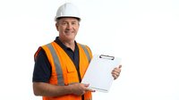 Middle-aged Caucasian male construction worker wearing white hard hat and orange safety vest over dark shirt, holding clipboard, smiling at camera against white background. For construction, safety, industrial, and occupational use.