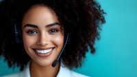 Young African American female customer service representative with curly afro hair and headset smiling against turquoise background, expressing positive attitude.
