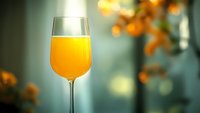 Glass of fresh orange juice with blurred warm bokeh background, suitable for beverage, health, breakfast and wellness marketing materials.