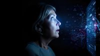 Middle-aged Caucasian businesswoman gazing at futuristic holographic data visualization with glowing blue digital interface and network connections.
