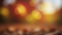 Abstract warm bokeh background with golden orange lights and blurred wooden surface for product display and seasonal marketing campaigns.
