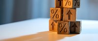Wooden blocks stacked in a tower with percent signs and upward arrows, symbolizing rising interest rates, financial growth, and economic trends.