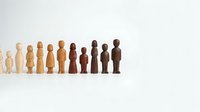 Wooden figurines in varying skin tones arranged in a line, representing diversity and inclusion. Suitable for business, community, and social concepts.