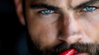 Close up portrait of young Caucasian male model with bright blue eyes and dark beard biting red chili pepper, dramatic lighting creates mysterious mood.