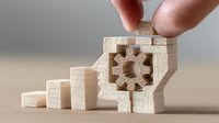 Fingers placing final piece in wooden puzzle with gear mechanism, symbolizing business solution and strategic problem-solving process.