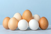 Fresh brown and white chicken eggs arranged in balanced composition against light blue background, showcasing natural organic food variety and texture.