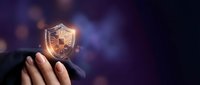 Glowing golden shield with security lock symbol held in hand against blurred purple background, representing data protection and cybersecurity solutions.