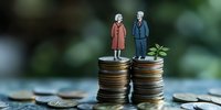 Senior couple figurines standing on uneven coin stacks representing gender pay gap, retirement savings inequality and financial disparity between men and women.