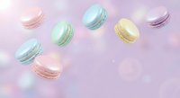 Colorful macarons floating on soft pastel background with dreamy bokeh lights for bakery and confectionery designs.