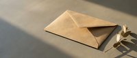 Kraft paper envelope on neutral surface with natural lighting and plant shadow creating minimalist composition for correspondence and stationery designs.