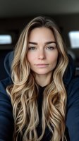 Young blonde Caucasian woman with wavy hair wearing navy hoodie looking at camera with natural makeup and confident expression for lifestyle content.