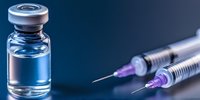Medical vial with transparent liquid and two disposable syringes on dark blue background, dramatic lighting creates professional pharmaceutical atmosphere.
