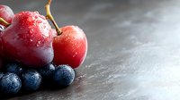 Fresh ripe cherries and blueberries with water drops on dark stone background, macro shot with selective focus and copy space for text.