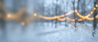 Winter snow pile with warm bokeh lights and bare trees creating cozy seasonal atmosphere for holiday decorations and festive backgrounds.