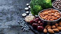 Fresh raw almonds, broccoli, blueberries, cherries and assorted nuts on dark stone background with copy space. Healthy vegan protein sources and superfoods.