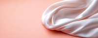 Elegant white silk fabric with soft folds and waves on coral pink background, luxury textile with smooth satin texture creating graceful drapery effect.