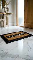 Welcome doormat with Greek key border on polished marble floor in a modern luxury entryway with wooden door and sculptural console.