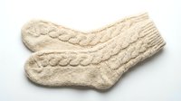 Pair of cozy cream cable-knit wool socks isolated on white background, perfect for winter fashion, holiday gift guides, and cold weather lifestyle content.