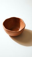 Handmade terracotta clay bowl with organic shape and natural texture on neutral background for kitchen and dining decor.