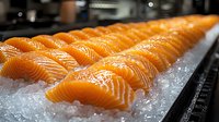 Fresh salmon sushi pieces lined up on crushed ice, showing vibrant orange color and precise cuts in restaurant setting, close-up view with selective focus.