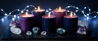 Purple and blue candles burning with crystals and fairy lights creating mystical atmosphere for meditation, spirituality and relaxation rituals.