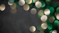Abstract bokeh lights background with green and golden circles creating dreamy atmosphere for holiday celebrations and festive decorations.