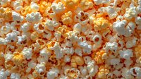Fresh popcorn with white and yellow kernels, creating a textured snack background for movie night or party food photography.