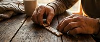 Skilled craftsman hands using traditional woodworking chisel on weathered wooden surface, showcasing artisan craftsmanship and manual woodcarving techniques.