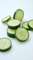 Fresh cucumber slices cut into rounds showing seeds and flesh, isolated on white background for healthy eating and cooking concepts.