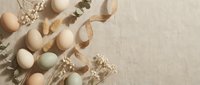 Natural Easter eggs in pastel colors with dried flowers and eucalyptus branches on neutral linen background for spring holiday decoration and crafting.