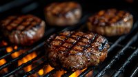 Juicy beef burger patties grilling on barbecue grate with fire flames below. Close-up of meat with appetizing char grill marks and caramelized surface.