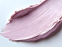 Soft pink cosmetic cream texture smeared in delicate feather-like stroke on white surface shows smooth creamy consistency and luxurious skincare product application.