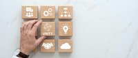 Business hand arranging wooden blocks with teamwork icons including unity, collaboration, leadership and partnership symbols on white background.