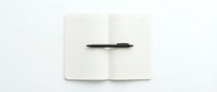 Open notebook with lined pages and black pen on white background for writing, journaling, note-taking and office work projects.