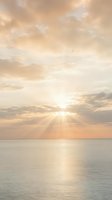 Serene ocean sunrise with golden sunrays breaking through soft clouds, calm water reflecting warm light, peaceful coastal seascape for travel and wellness projects.