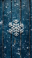 White decorative snowflake on dark blue wooden planks background with scattered snow powder creating festive winter holiday atmosphere.