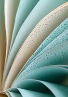 Curved pages of book in soft mint green and beige tones create abstract waves with delicate dotted texture pattern, macro photography for artistic background.