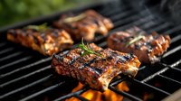 Juicy glazed pork ribs grilling on barbecue with flames and smoke. Fresh rosemary garnish adds aromatic touch to charred meat with caramelized sauce.
