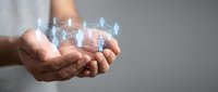 Human hands holding glowing translucent figures representing team support, leadership and community connection in business environment.