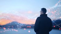 Man in silhouette gazing at mountain landscape with digital network overlay and bokeh lights against sunset sky, representing technology and nature connection.