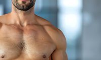 Muscular male torso with beard stubble shown in close-up against blurred background, demonstrating strength and fitness for health and wellness concepts.