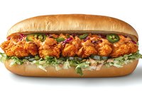 Crispy fried chicken sandwich with fresh lettuce, pickled jalapeños and creamy sauce on toasted sub roll isolated on white background for food design.