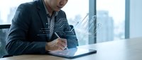Man in dark blazer writing on tablet with digital wave overlay, modern office cityscape background, technology and business concept.