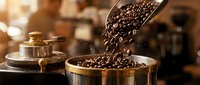 Fresh roasted coffee beans pouring from scoop into vintage brass container in warm artisanal cafe setting for coffee shop branding and beverage marketing.