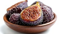 Fresh ripe purple figs in rustic ceramic bowl, one cut in half showing juicy red interior with seeds, on white background for food photography.