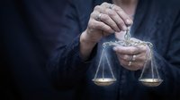 Businessman holding golden scales of justice in hands representing legal balance, fairness and judicial system in corporate law and business ethics.